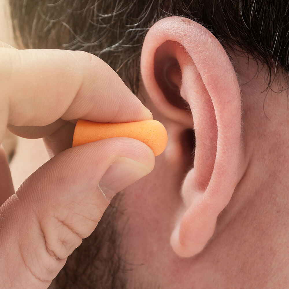 man putting ear plugs into ear